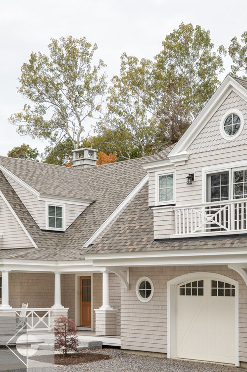 View of Boothbay Harbor home featuring garage and wrap around porch.