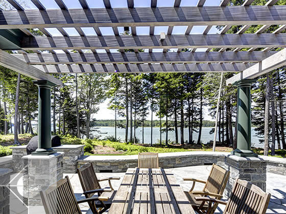 Outdoor eating area with water views in Cushing, Maine by Phelps Architects.