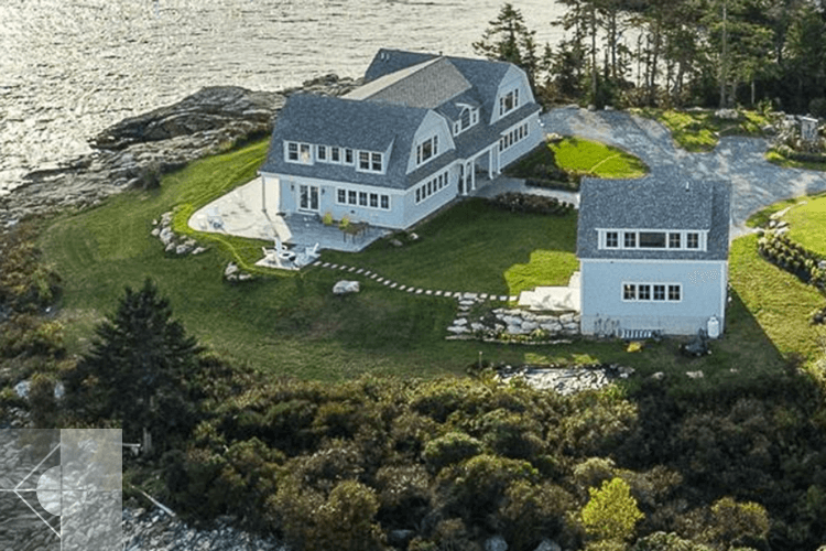 Aerial view of gambrel style home and guest house, both overlooking the ocean.