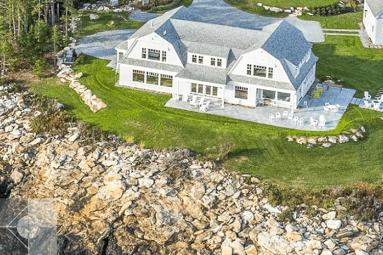 Drone image of house from the ocean showing large windows and stone outdoor area.