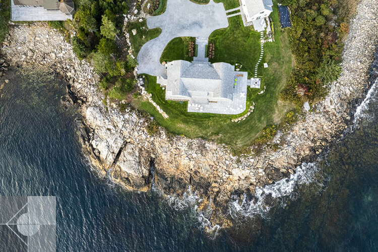 Overhead view of the house, guest house, driveway, rock wall and ocean.
